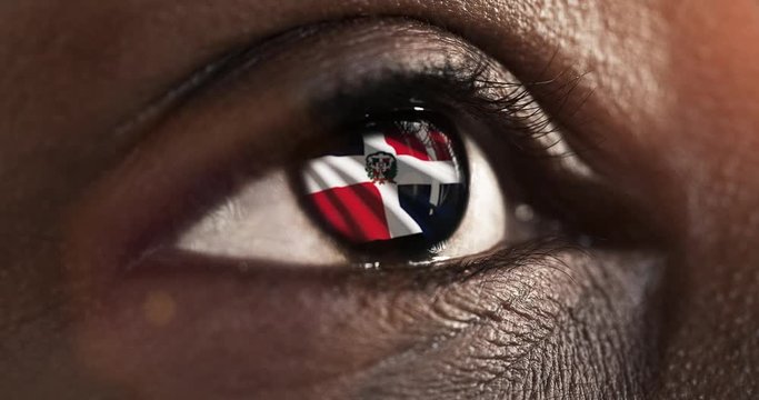 Woman black eye in close up with the flag of Dominican republic in iris with wind motion. video concept