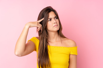 Teenager Brazilian girl over isolated pink background making the gesture of madness putting finger on the head