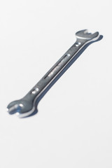 Open end chrome wrench on white surface.