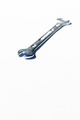 Open end chrome wrench on white surface.