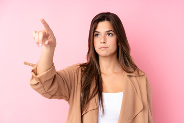 Teenager Brazilian girl over isolated pink background touching on transparent screen