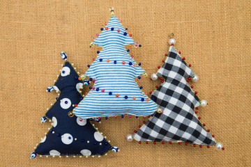 3 Handmade  textile cotton fabric naive retro style Christmas trees ornament decorated with beads on burlap background