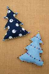 2 handmade stripped and polka dot textile cotton fabric naive retro style Christmas tree ornament decorated with beads on burlap background