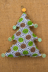 Handmade green pattern  textile cotton fabric naive retro style Christmas tree ornament decorated with beads on burlap background