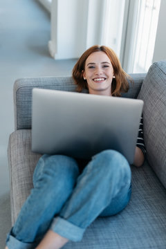 Casual young woman relaxing with a laptop