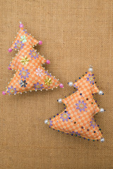 Handmade orange floral  textile cotton fabric naive retro style Christmas tree ornament decorated with beads on burlap background