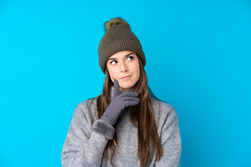 Teenager girl with winter hat over isolated blue background thinking an idea