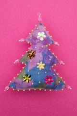 Handmade floral purple  blue textile cotton fabric naive retro style Christmas tree ornament decorated with beads on pink background