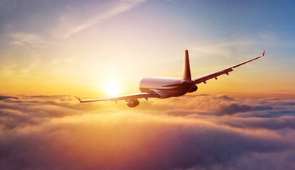 Passengers commercial airplane flying above clouds in sunset light. Concept of fast travel,...