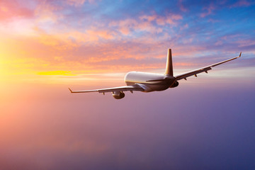 Passengers commercial airplane flying above clouds in sunset light. Concept of fast travel, holidays and business.