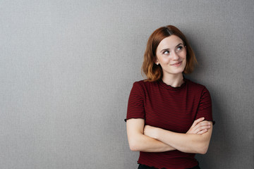 Pretty young woman standing thinking with a smile