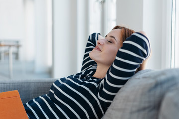 Obraz premium Blissful young woman relaxing at home on a sofa