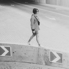 Black and white shot of Young adult female walking on parking