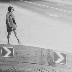 Black and white shot of Young adult female walking on parking