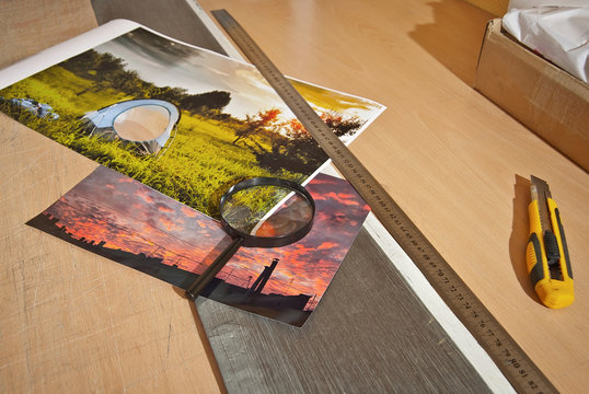 Manually crop photos. Printed photos on the table. Knife and ruler on the table. Framing pictures with a stationery knife.