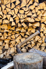 Axe in a stump near the stack of firewood