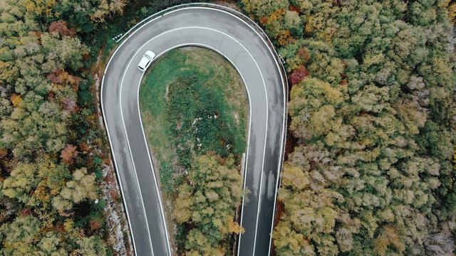 Winding road through a forest, car taking a sharp turn