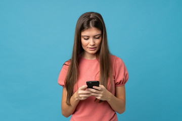 Fototapeta premium Young woman over isolated blue background sending a message or email with the mobile