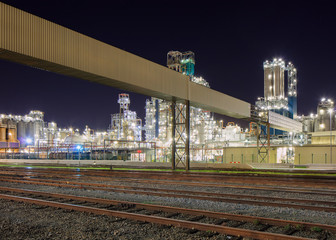Fototapeta premium Night scene with illuminated petrochemical production plant and train rails on the foreground, Antwerp, Belgium.