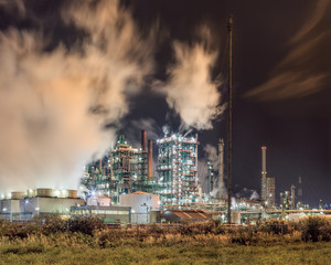 Night scene with view on petrochemical production plant with plumes of smoke, Port of Antwerp, Belgium.