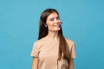 Young woman over isolated blue background working with headset