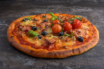 Homemade pizza with ham, tomatoes, cheese and basil