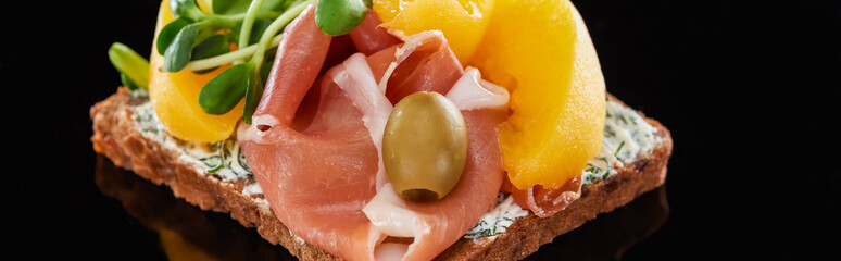 panoramic shot of ham and canned peaches on danish smorrebrod sandwich on black