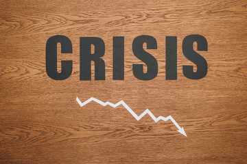 top view of black paper cut word crisis and recession arrow on wooden desk