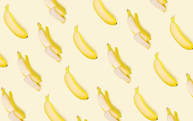 Obraz premium Whole and open bananas on a light background. Vegetarian concept. Creative drawing, minimalism, top view, flat lay. Tasty and healthy food.