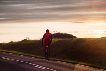 Obraz premium cyclist climbing a slope at sunset