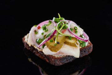 close up of herring fish on danish smorrebrod sandwich on black