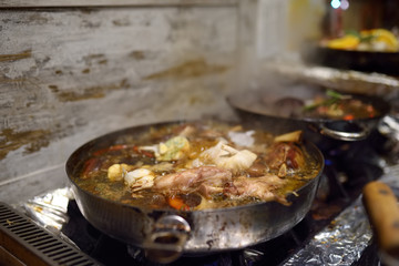 Traditional food at the Christmas street market - stewed pork. This course is cooking from pork, onion, garlic and carrots in a frying pan.