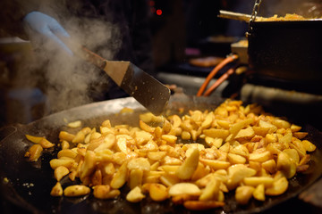 Hot food on Tallinn Christmas fair. Fried potatoes in large kitchen pan.