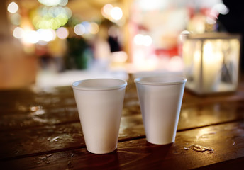 Pair of disposable cups on a wooden table on Christmas street market. Xmas holidays on famous fair in Tallinn, Estonia.