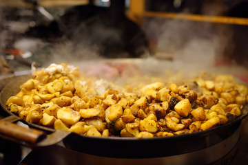 Hot food on Tallinn Christmas fair. Fried potatoes in large kitchen pan.