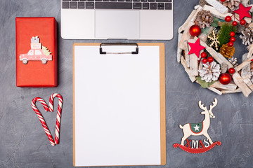 Christmas New Year creative holiday desktop with laptop, wreath, gift box candy cane blank paper. Copy space. Moke up. 