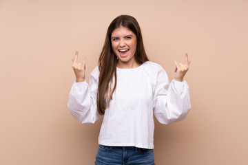 Young girl over isolated background making rock gesture