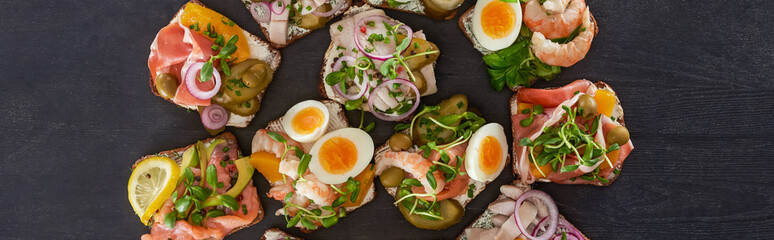 panoramic shot of rye bread with tasty smorrebrod sandwiches on grey