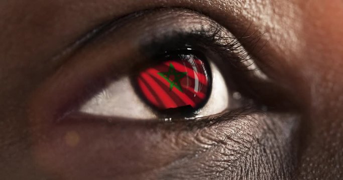 Woman black eye in close up with the flag of Morocco in iris with wind motion. video concept