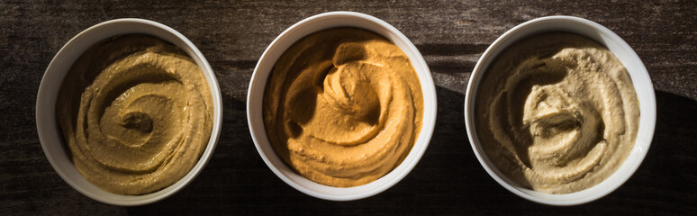 top view of delicious assorted hummus on wooden rustic table, panoramic shot