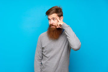 Redhead man with long beard over isolated blue background making the gesture of madness putting...