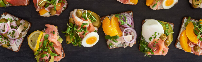 panoramic shot of rye bread with tasty smorrebrod sandwiches on grey surface