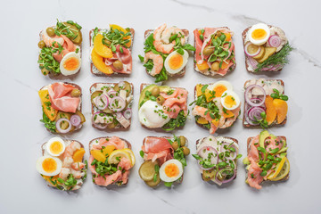 top view of danish smorrebrod sandwiches on white marble surface