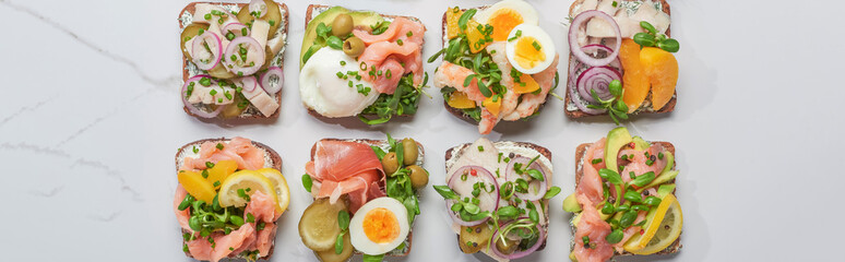 panoramic shot of fresh danish smorrebrod sandwiches on white marble surface
