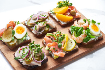 tasty smorrebrod sandwiches on wooden chopping board on white