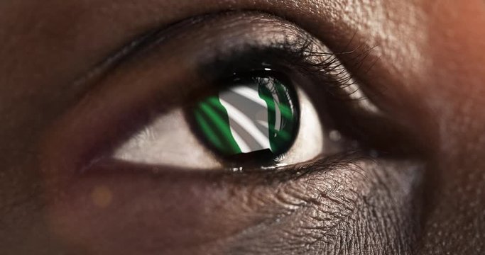 Woman black eye in close up with the flag of Nigeria in iris with wind motion. video concept