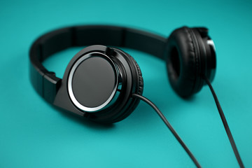 Black headphones on the turquoise background. Music concept.