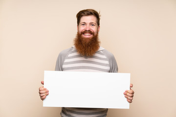 Redhead man with long beard over isolated background holding an empty white placard for insert a concept