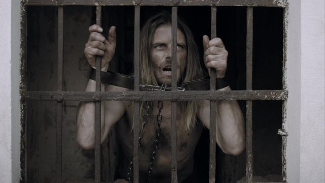 Desperate Prisoner Clinging To Bars Of Cell And Banging On Them