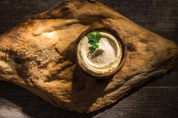 top view of delicious hummus near fresh baked pita on wooden rustic table